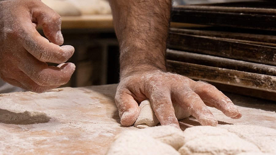 Hände, wie sie Teig kneten.