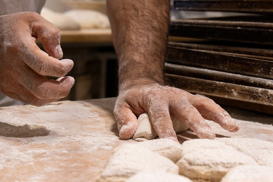 Hände, wie sie Teig kneten.