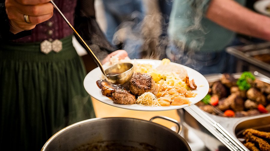 Teller mit deftigem Essen über Topf.